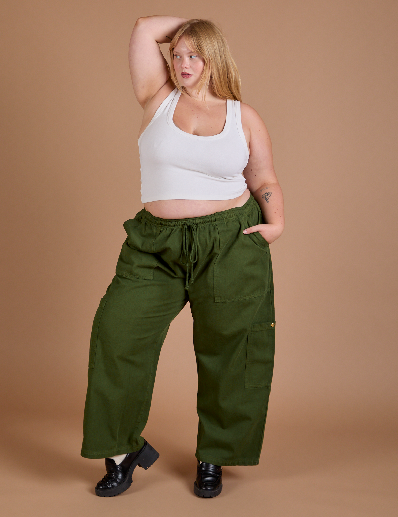 Juliet is 5’7” and wearing 1XL Drop Pocket Cargo Pants in Evergreen paired with a Cropped Tank in vintage tee white