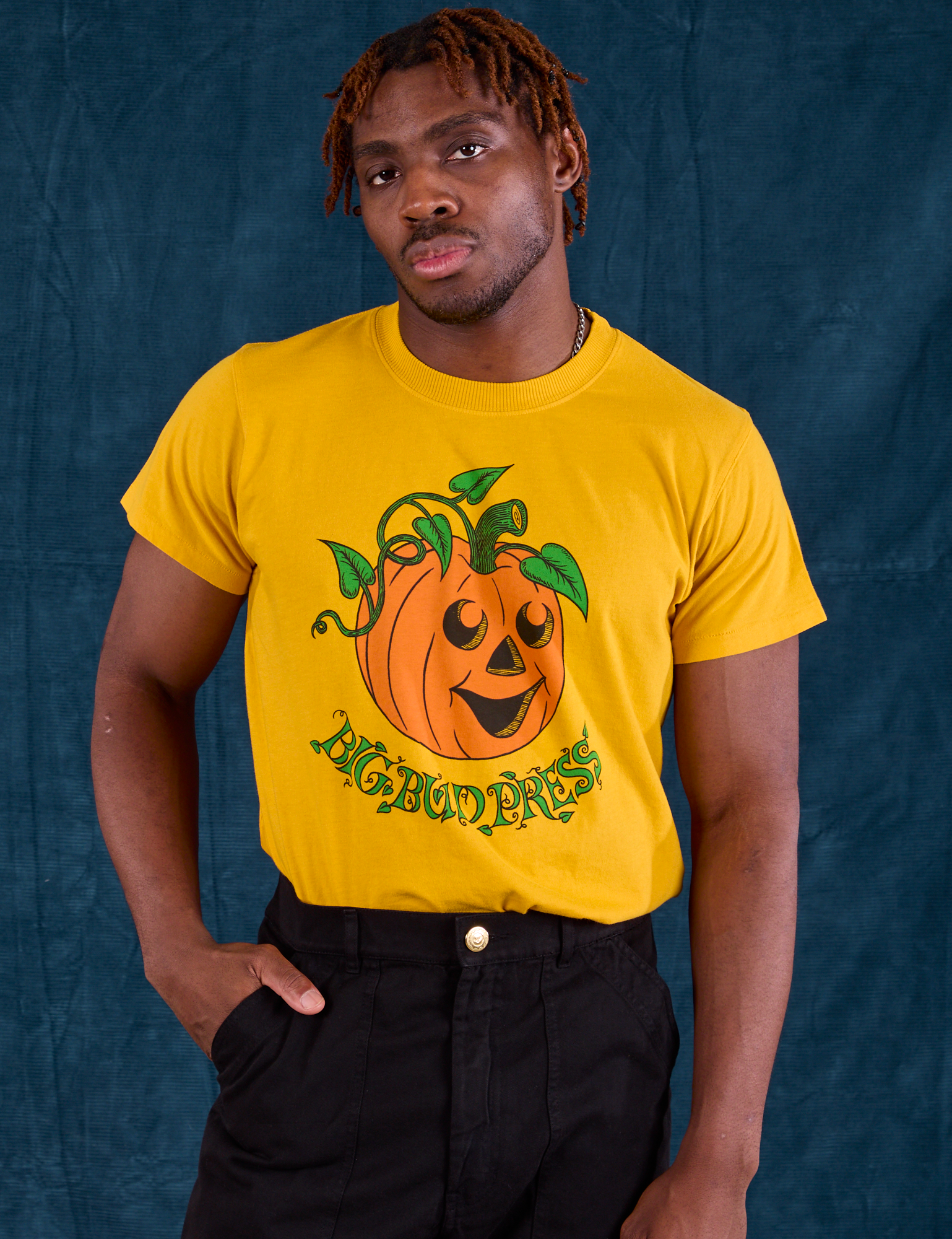 Issac is wearing Halloween Organic Tee in Pumpkin tucked into black Work Pants