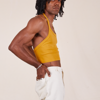 Side view of Halter Top in Mustard Yellow worn by Jerrod. They have their hands in the back pockets of the vintage off-white Western Pants.