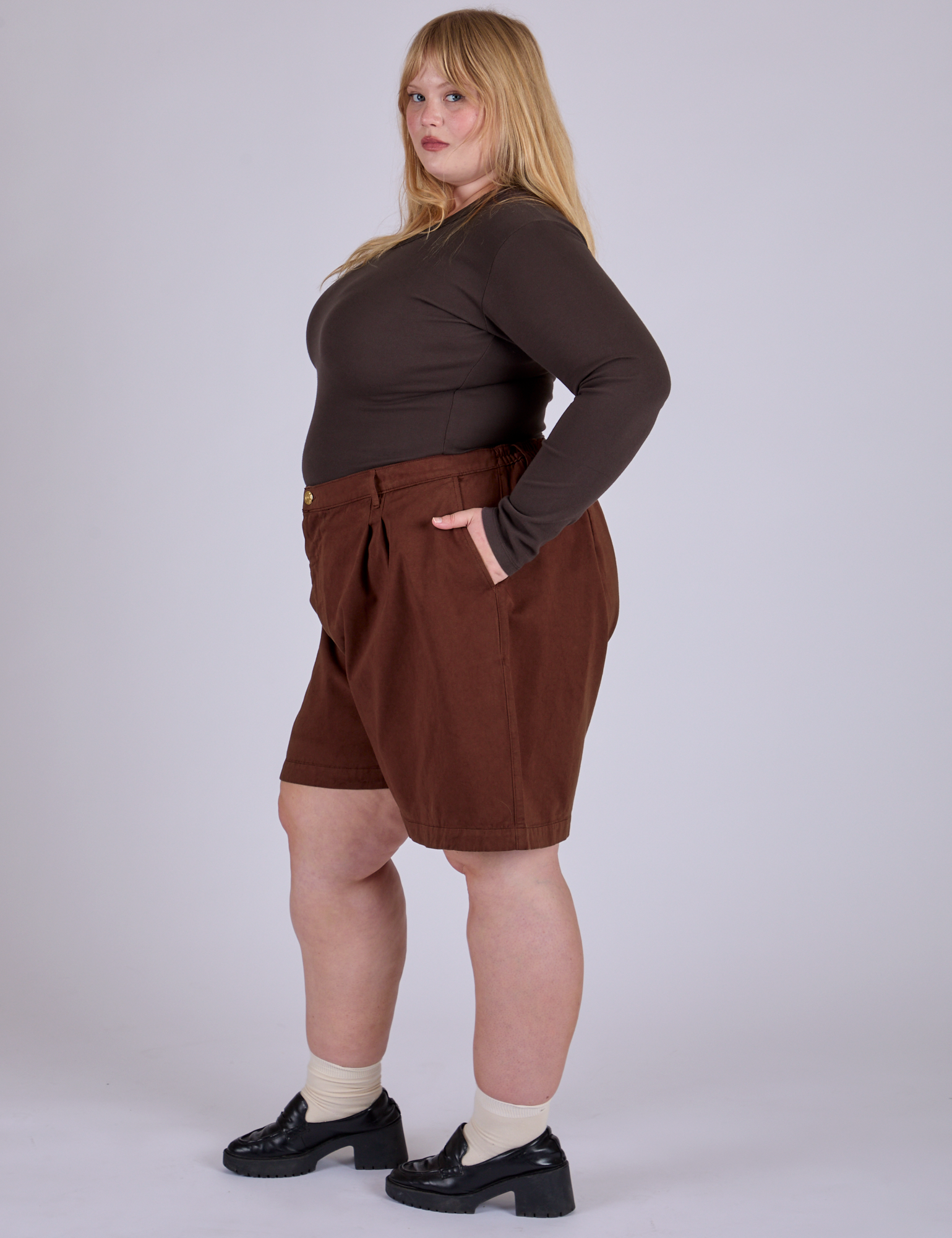 Side view of Pleated Trouser Shorts in Fudgesicle Brown and espresso brown Long Sleeve Baby Tee on Juliet
