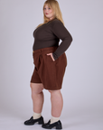 Side view of Pleated Trouser Shorts in Fudgesicle Brown and espresso brown Long Sleeve Baby Tee on Juliet