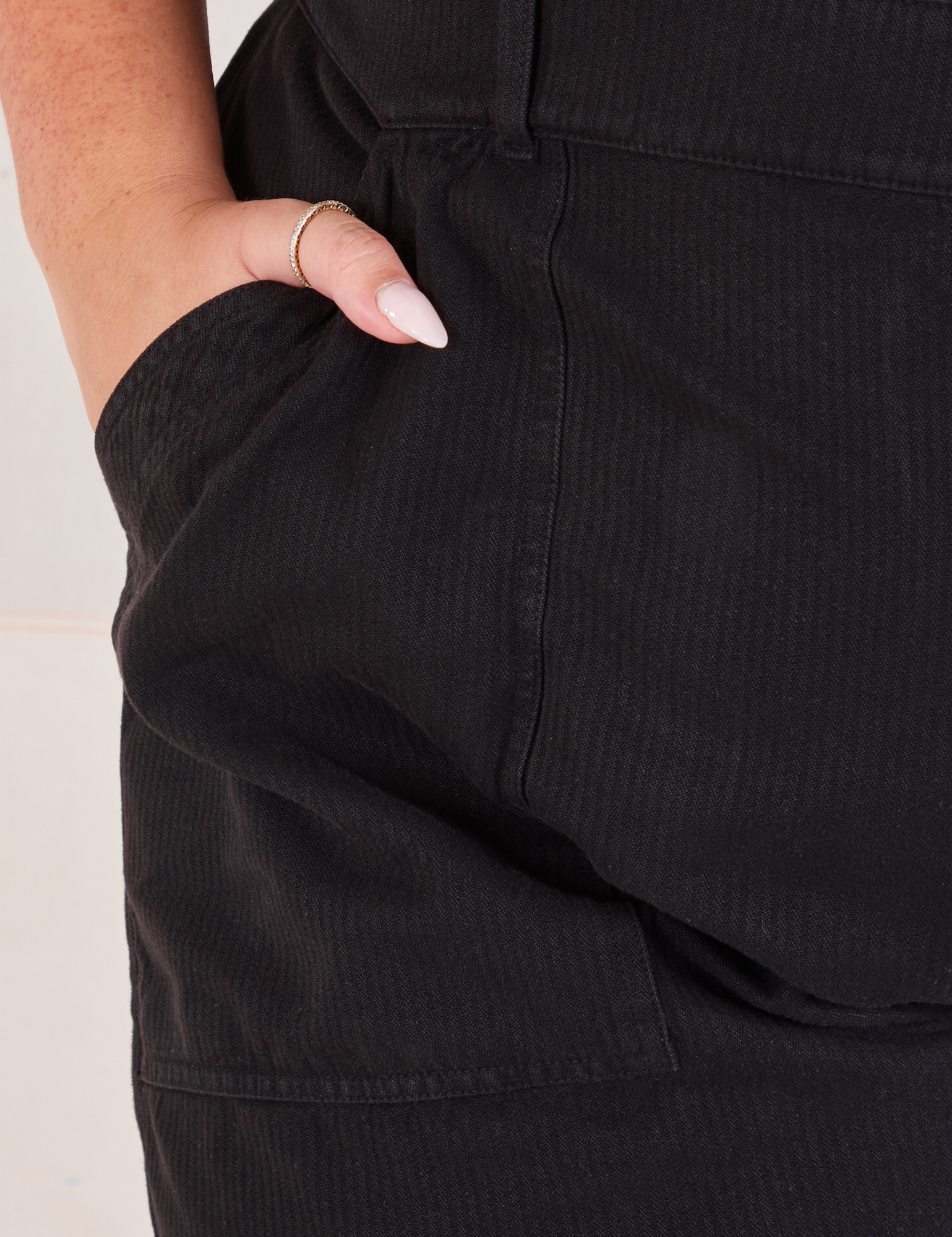 Heritage Short Sleeve Jumpsuit in Basic Black front pocket close up. Katie has her hand in the pocket.