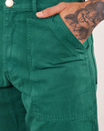 Front pocket close up of Work Pants in Hunter Green. Jesse has their hand in the pocket.