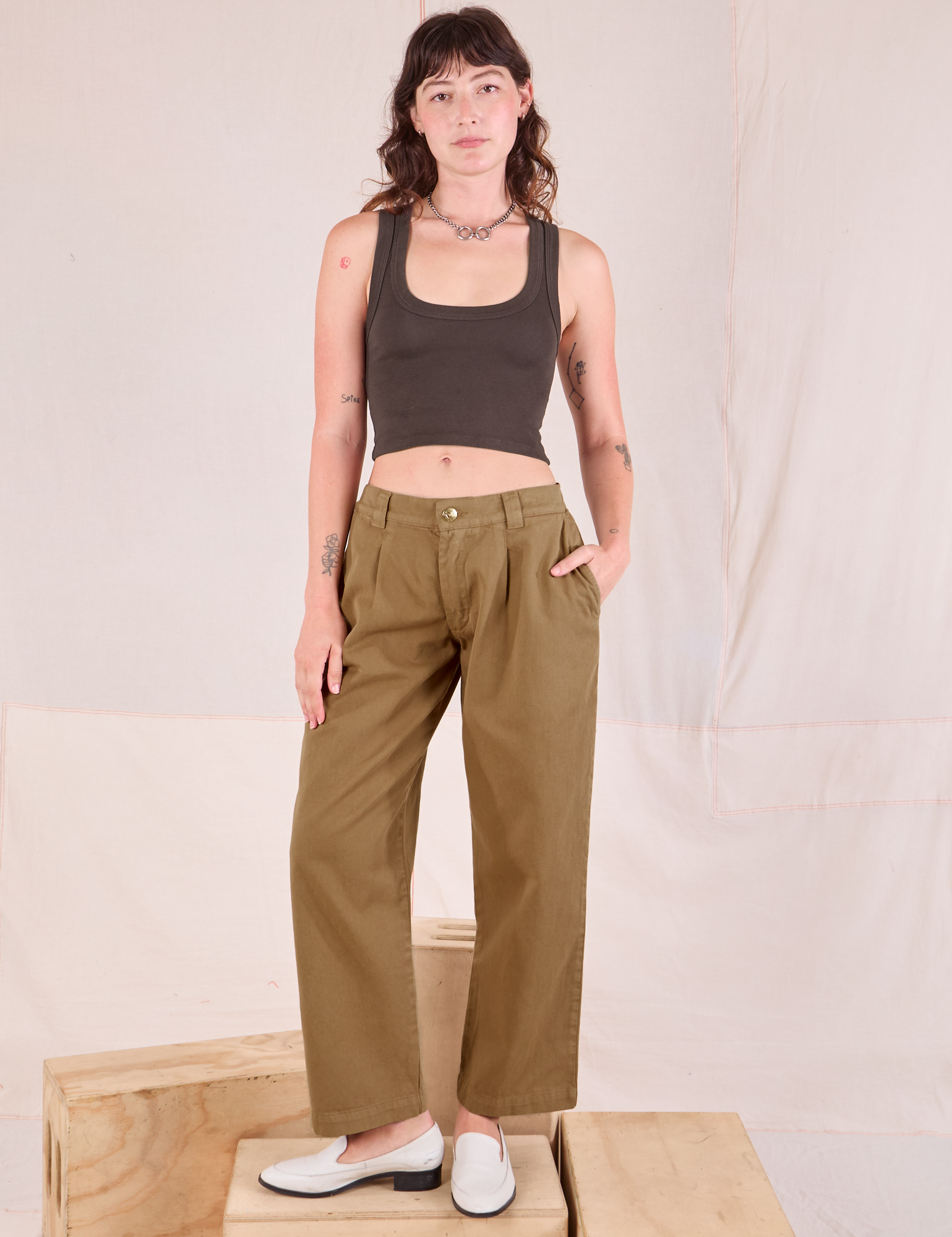 Alex is 5&#39;8&quot; and wearing XXS Mid-Rise Pleated Trousers in Desert Brown paired with espresso brown Cropped Tank