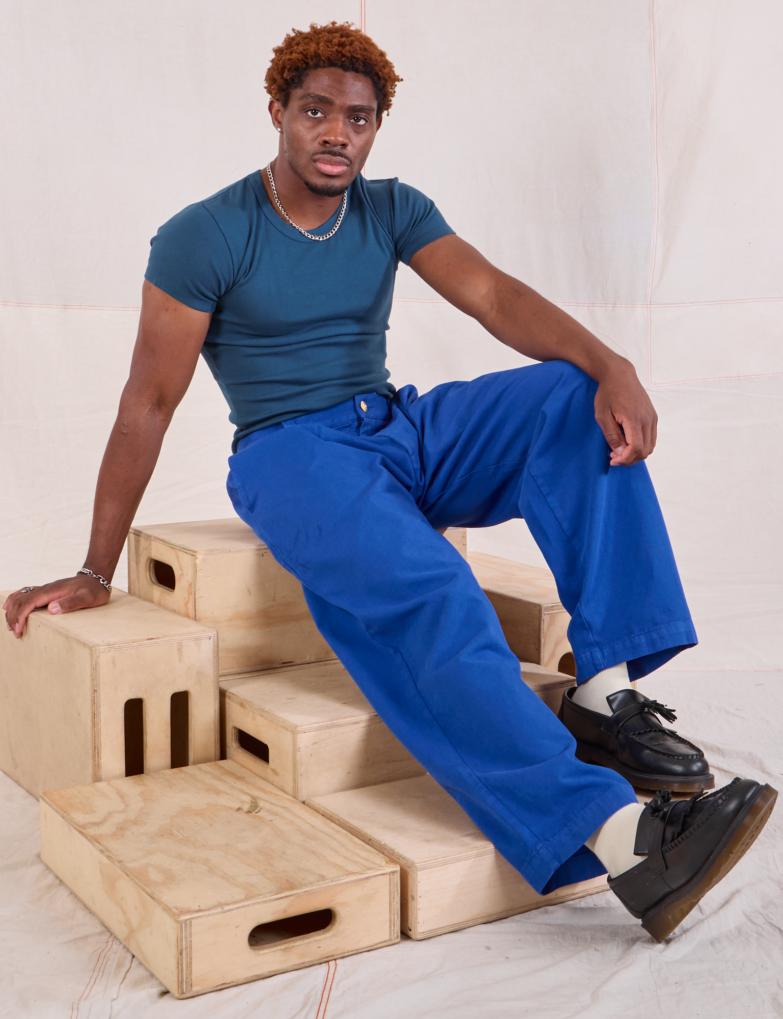 Issac is wearing Mid-Rise Pleated Trousers in Royal Blue and lagoon Baby Tee