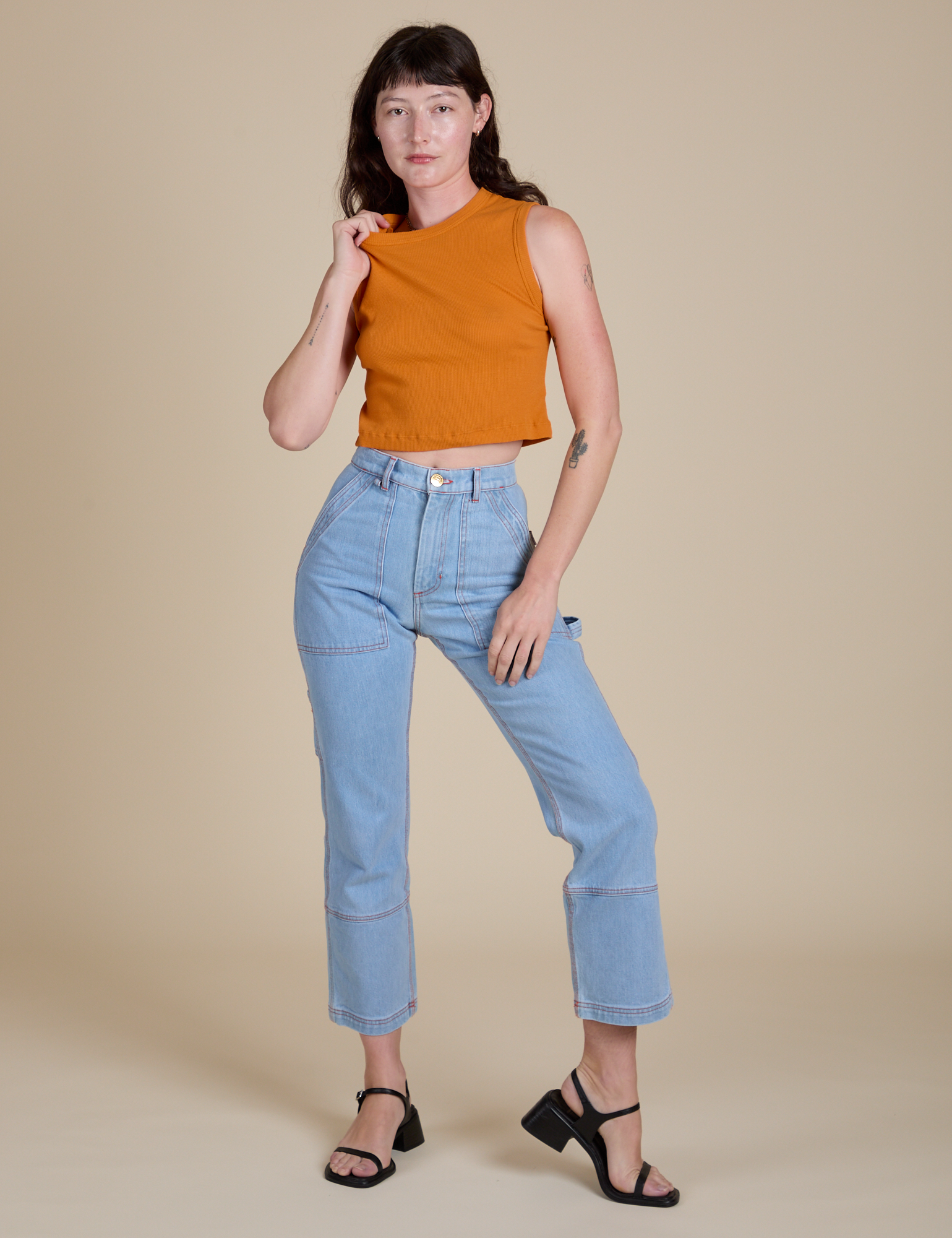 Alex is wearing Muscle Tee in Creamsicle Orange and light wash Carpenter Jeans