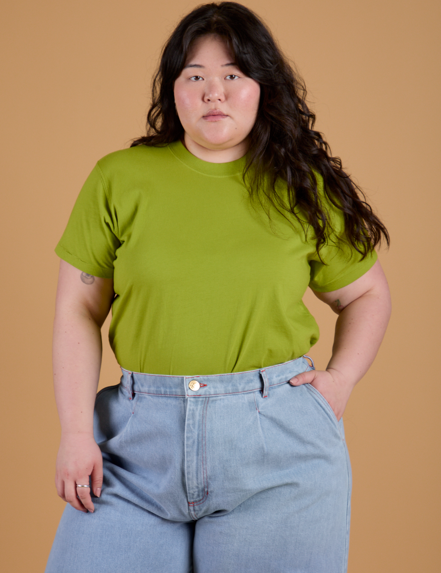 Ashley is wearing Organic Vintage Tee in Gross Green tucked into light wash Indigo Wide Leg Trousers