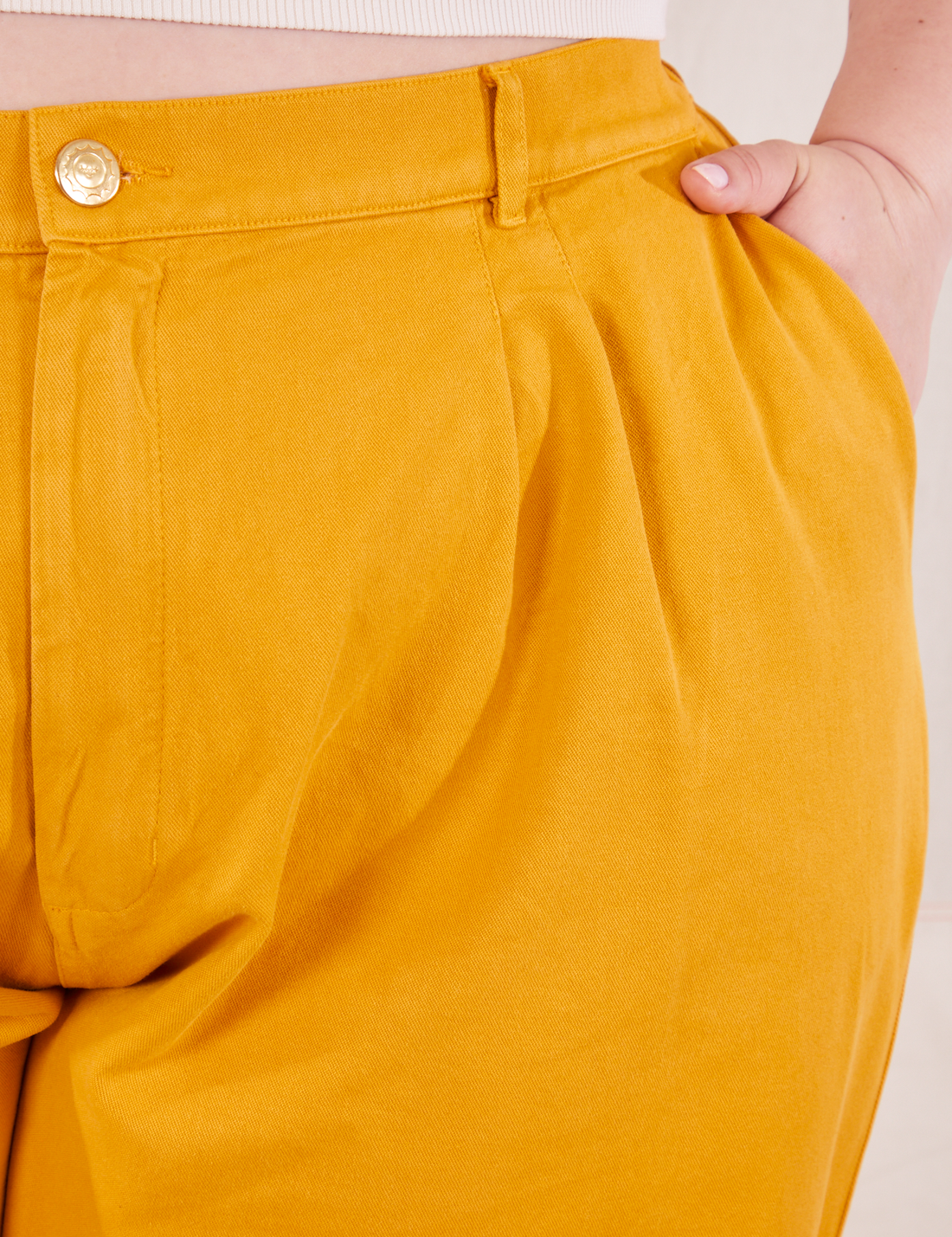 Front close up of Organic Trousers in Mustard Yellow. Ashley has her hand in the front pocket.