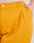 Front close up of Organic Trousers in Mustard Yellow. Ashley has her hand in the front pocket.
