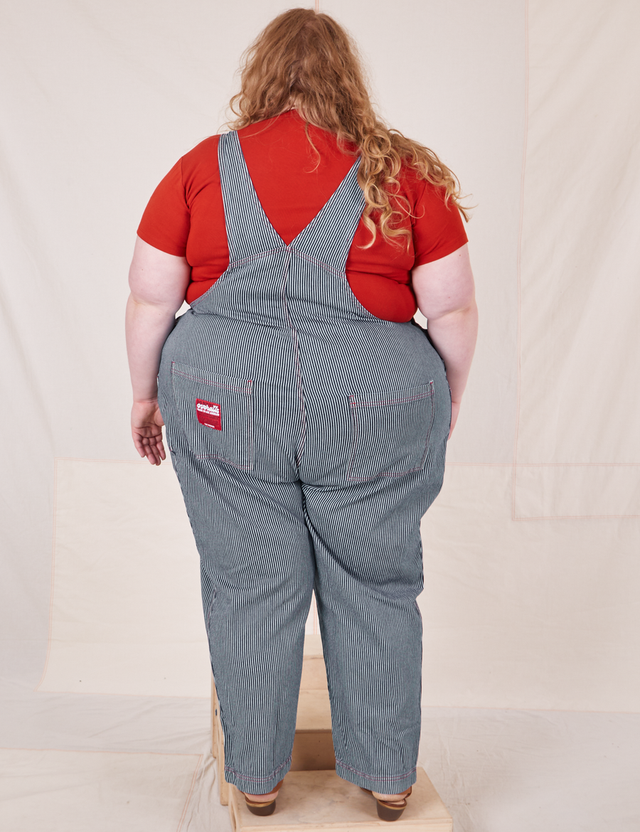 Back view of Railroad Stripe Denim Original Overalls and paprika Baby Tee worn by Catie
