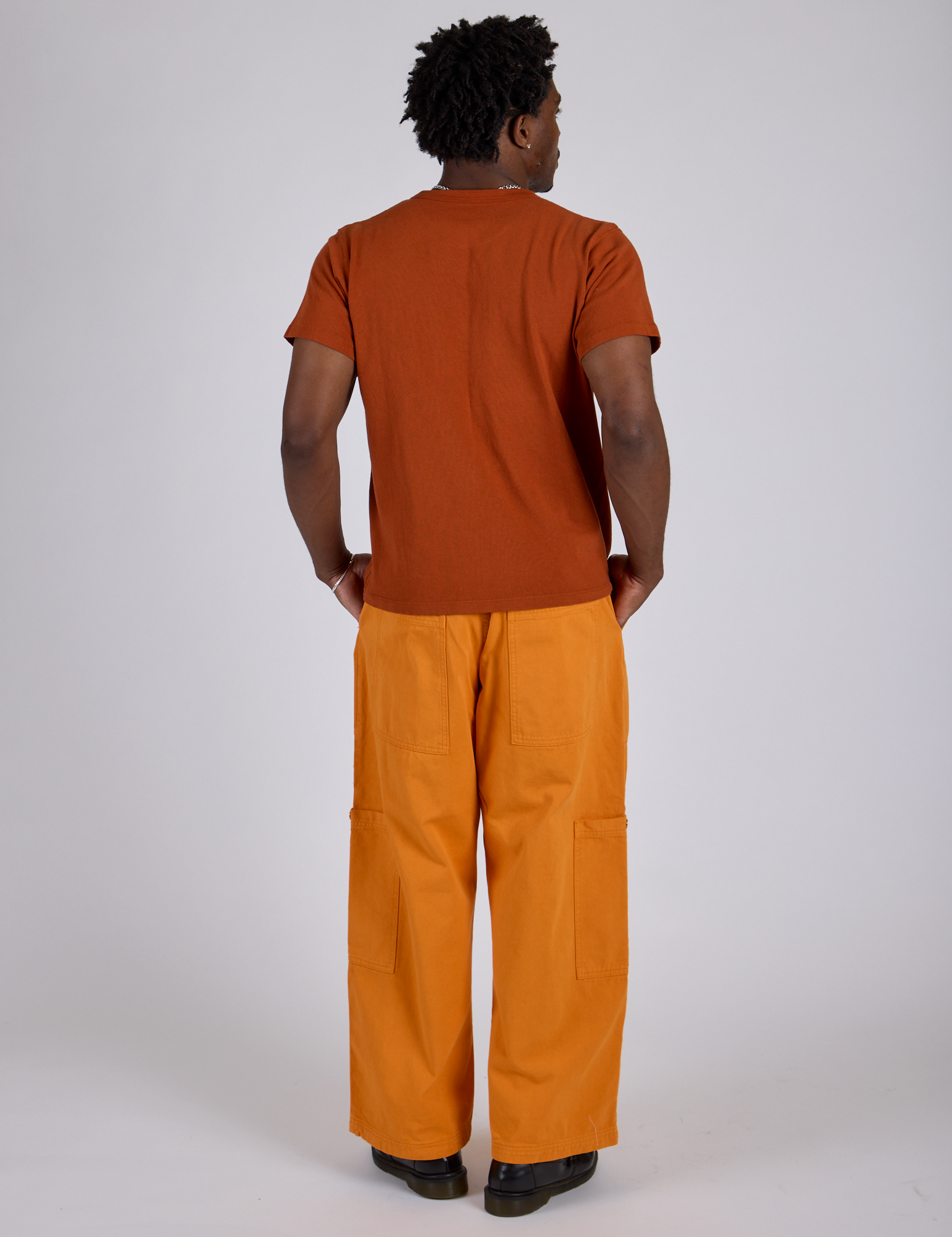 Back view of Drop Pocket Cargo Pants in Creamsicle Orange and burnt terracotta Organic Vintage Tee on Isaac
