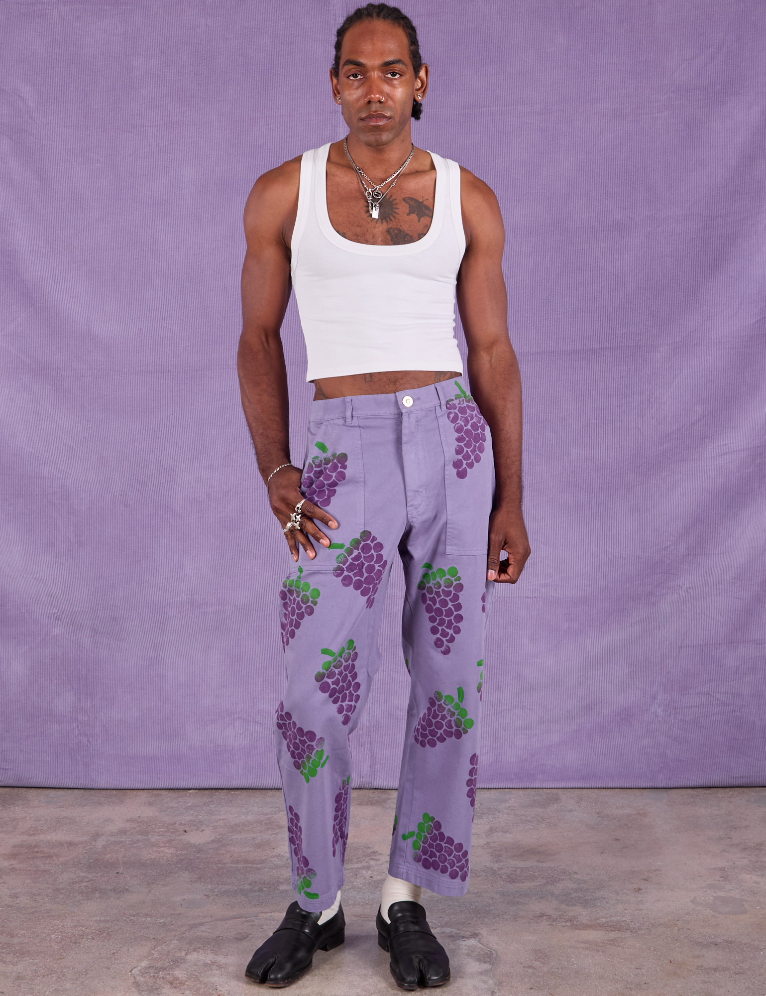 Jerrod is 6&#39;3&quot; and wearing M Paintstamped Work Pants in Grape paired with a Cropped Tank in Vintage Tee Off-White