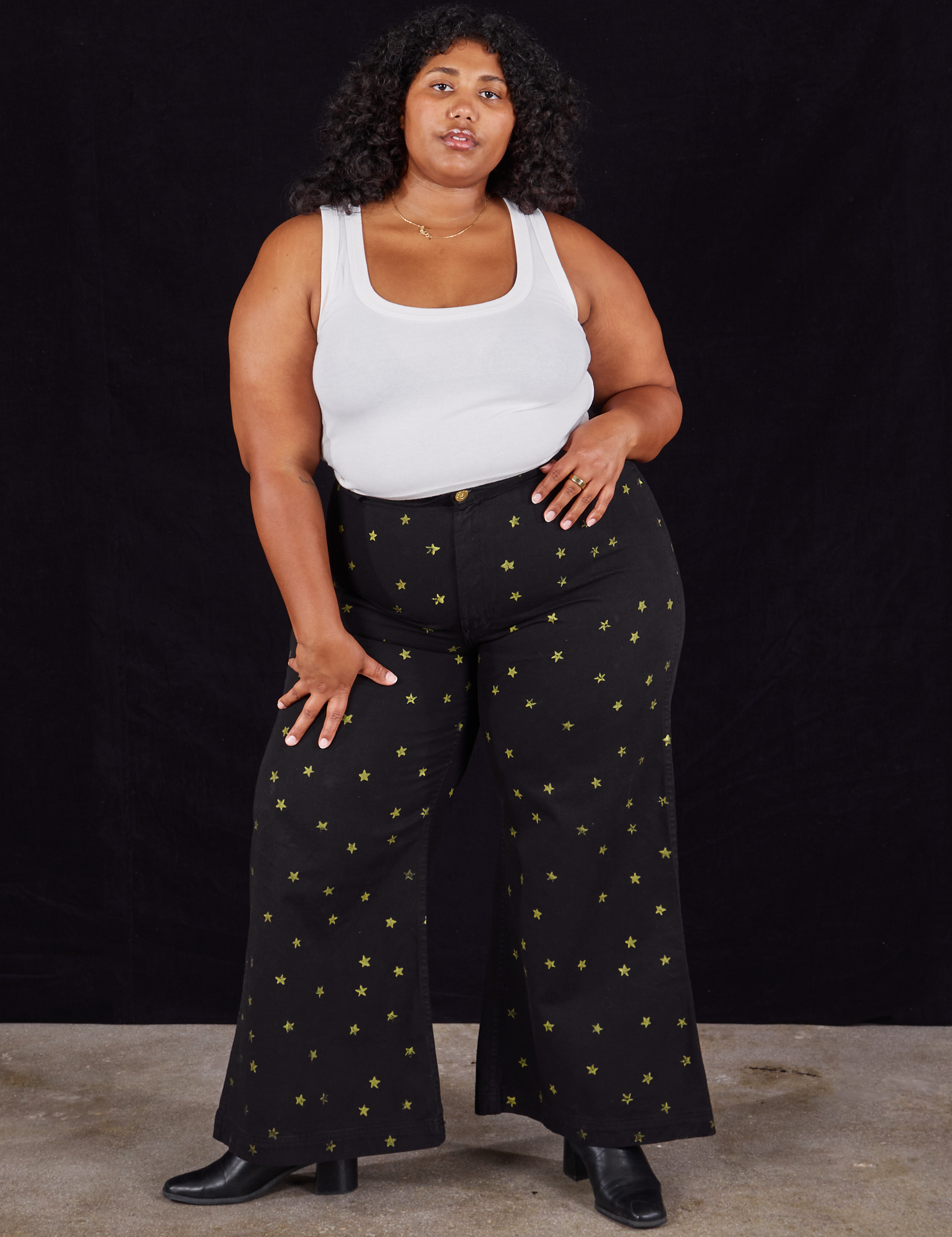 Morgan is 5&#39;5&quot; and wearing 1XL Star Bell Bottoms in Black paired with a Cropped Tank in vintage tee off-white