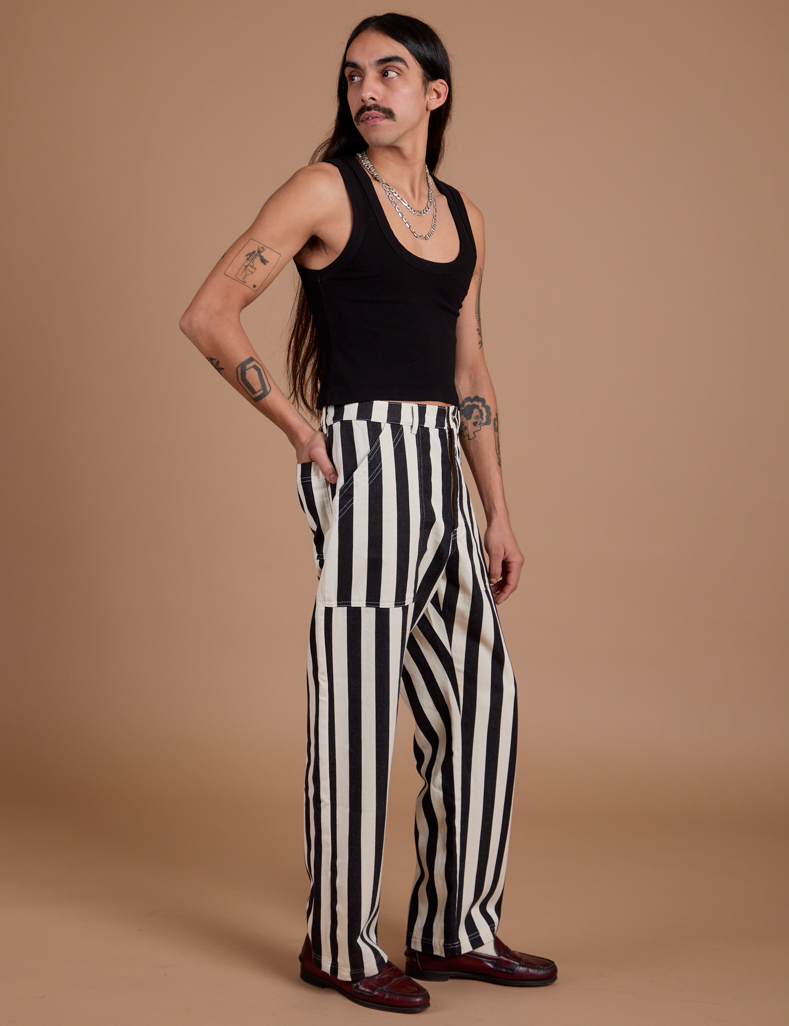 Side view of Black Stripe Work Pants in White and black Cropped Tank on Anthony