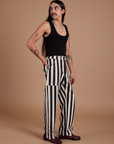 Side view of Black Stripe Work Pants in White and black Cropped Tank on Anthony