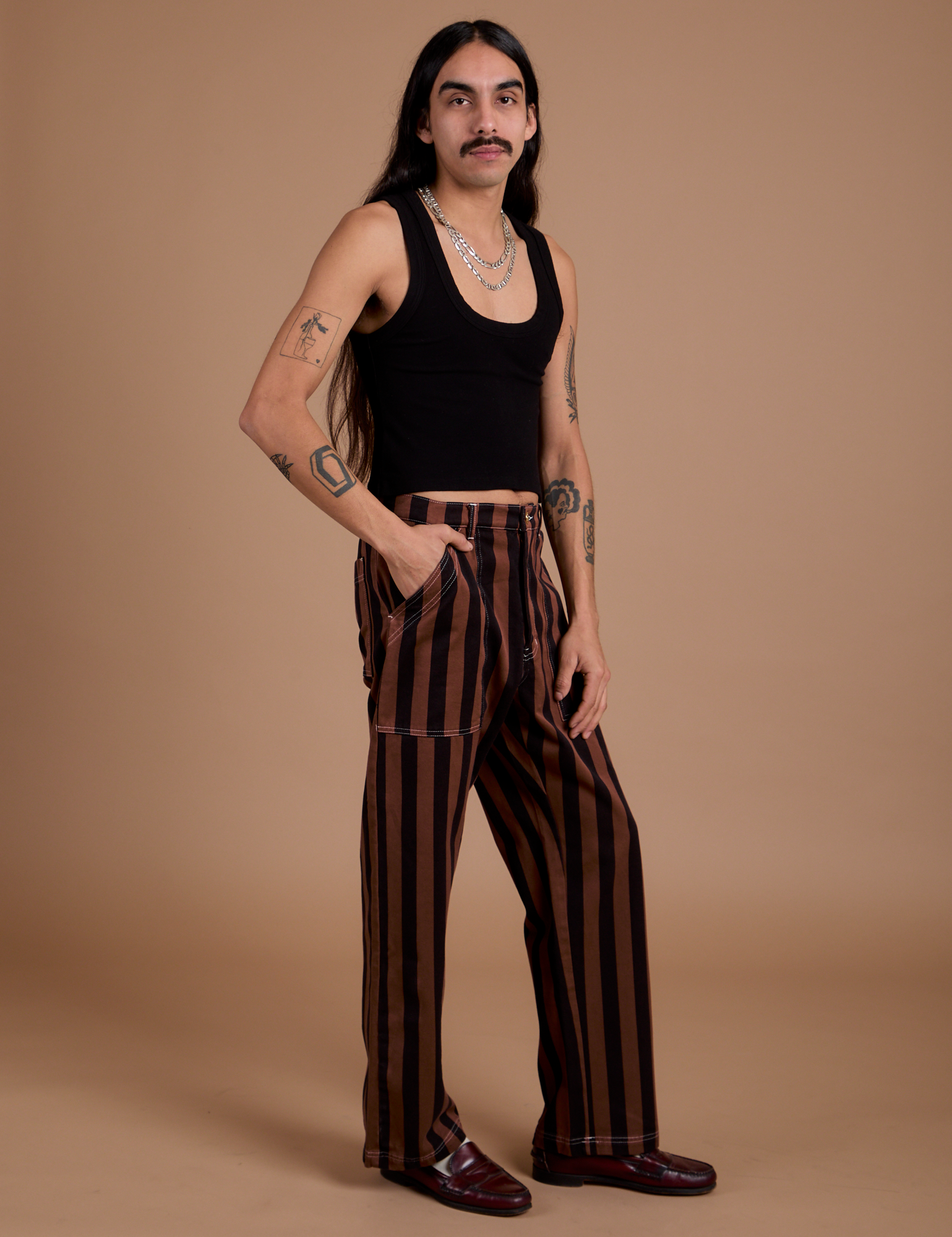 Angled front view of Black Stripe Work Pants in Fudgesicle Brown and black Cropped Tank on Anthony