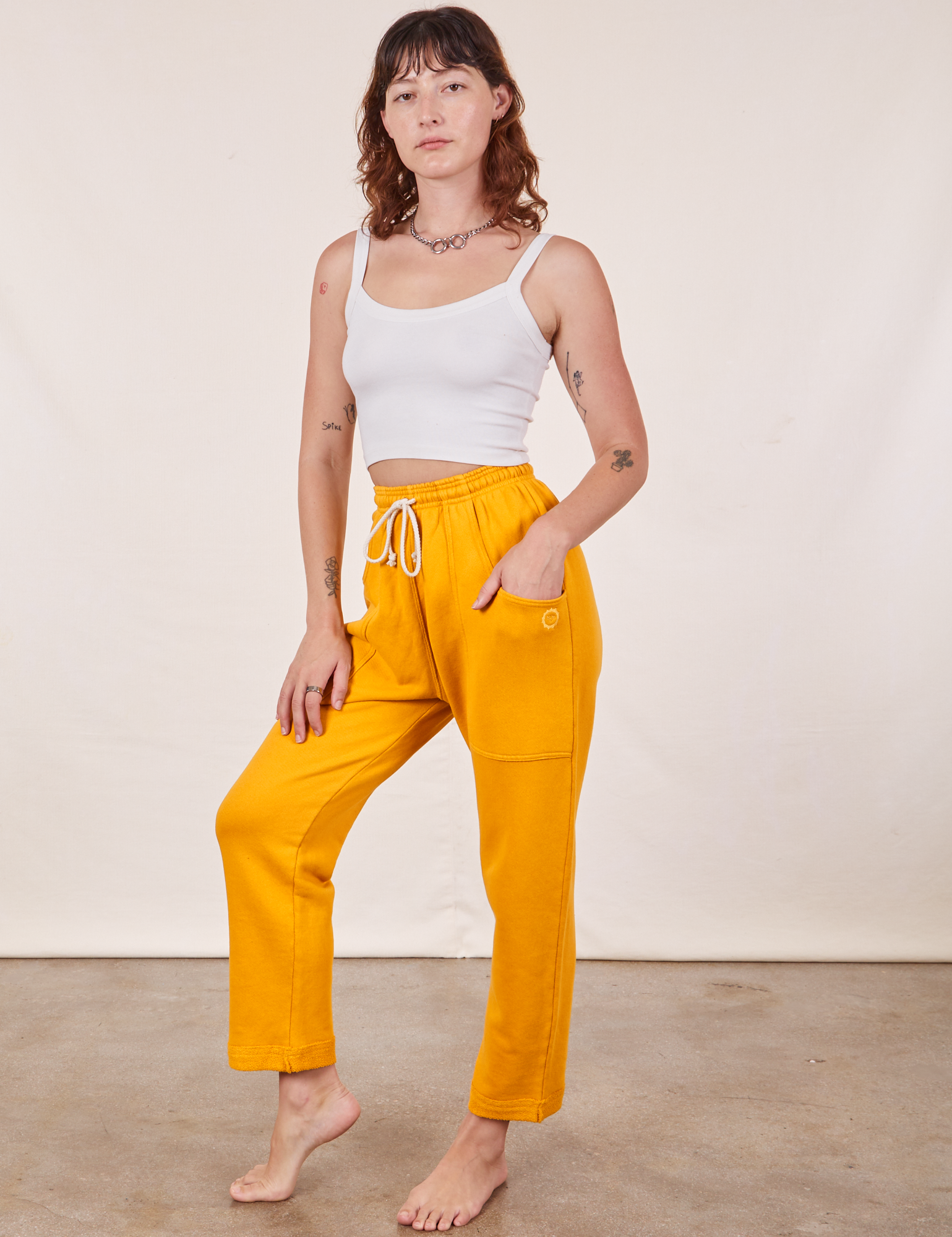 Alex is wearing Cropped Rolled Cuff Sweatpants in Mustard Yellow and vintage off-white Cami