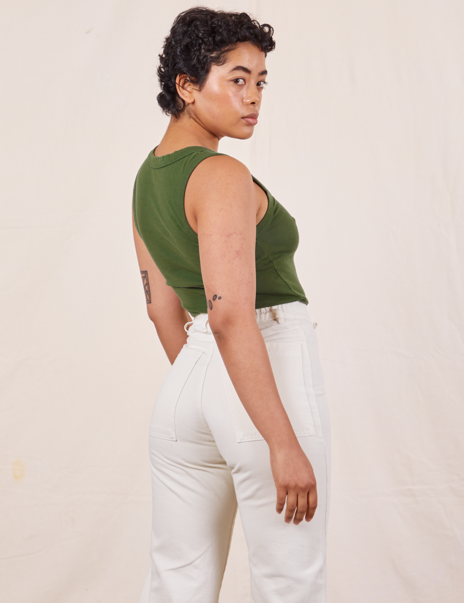 Angled back view of Tank Top in Dark Emerald Green on Mika