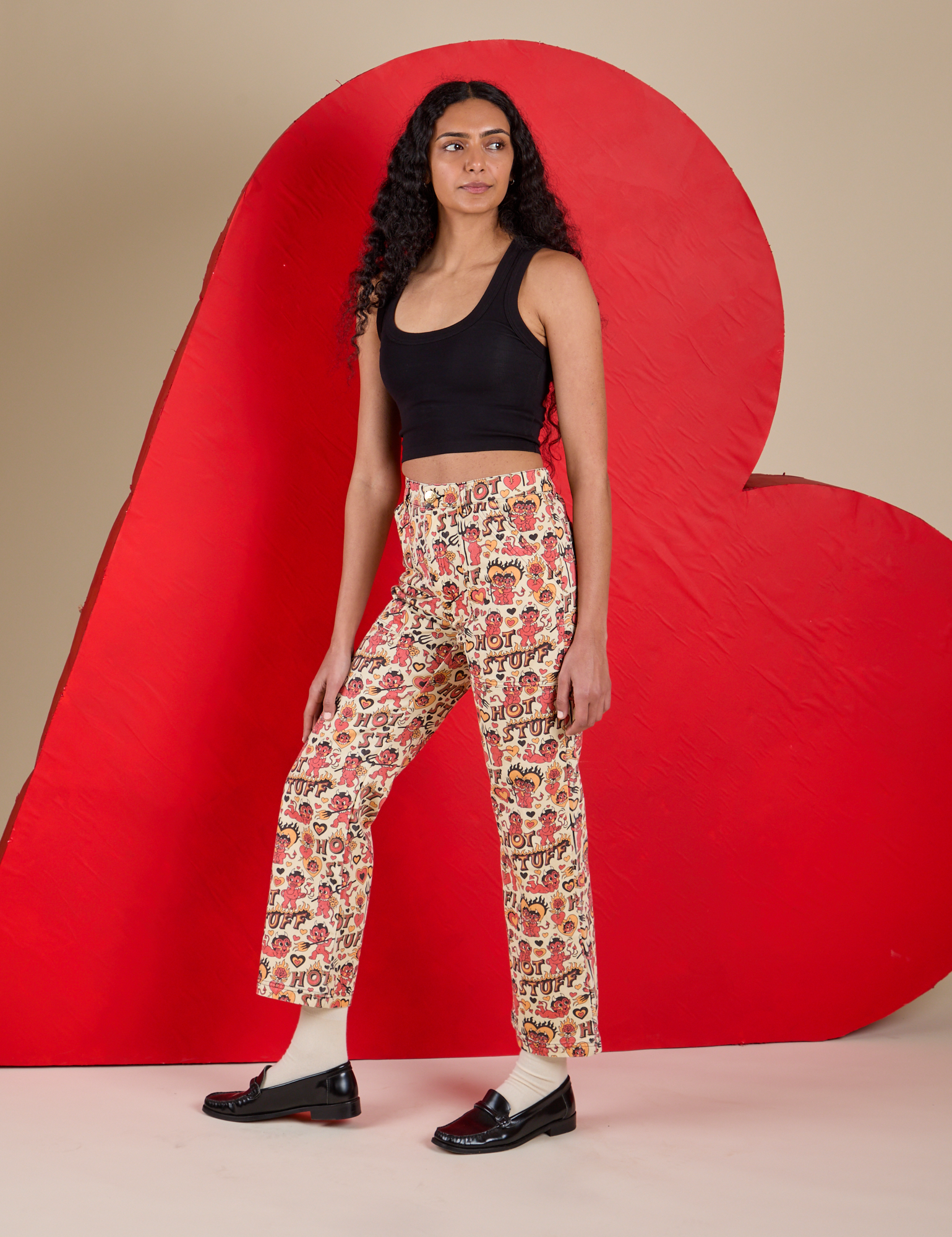 Angled front view of Work Pants in Hot Stuff Print and black Cropped Tank on Shahana
