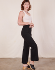 Side view of Western Pants in Basic Black and vintage off-white Tank Top worn by Alex