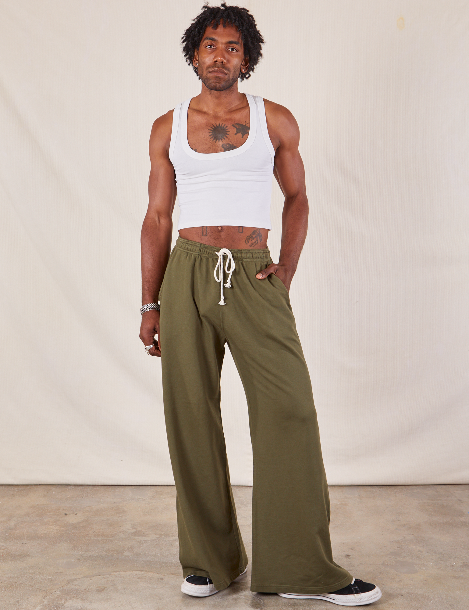 Jerrod is 6&#39;3&quot; and wearing S Wide Leg Sweat Pants in Surplus Green paired with Cropped Tank in vintage tee off-white