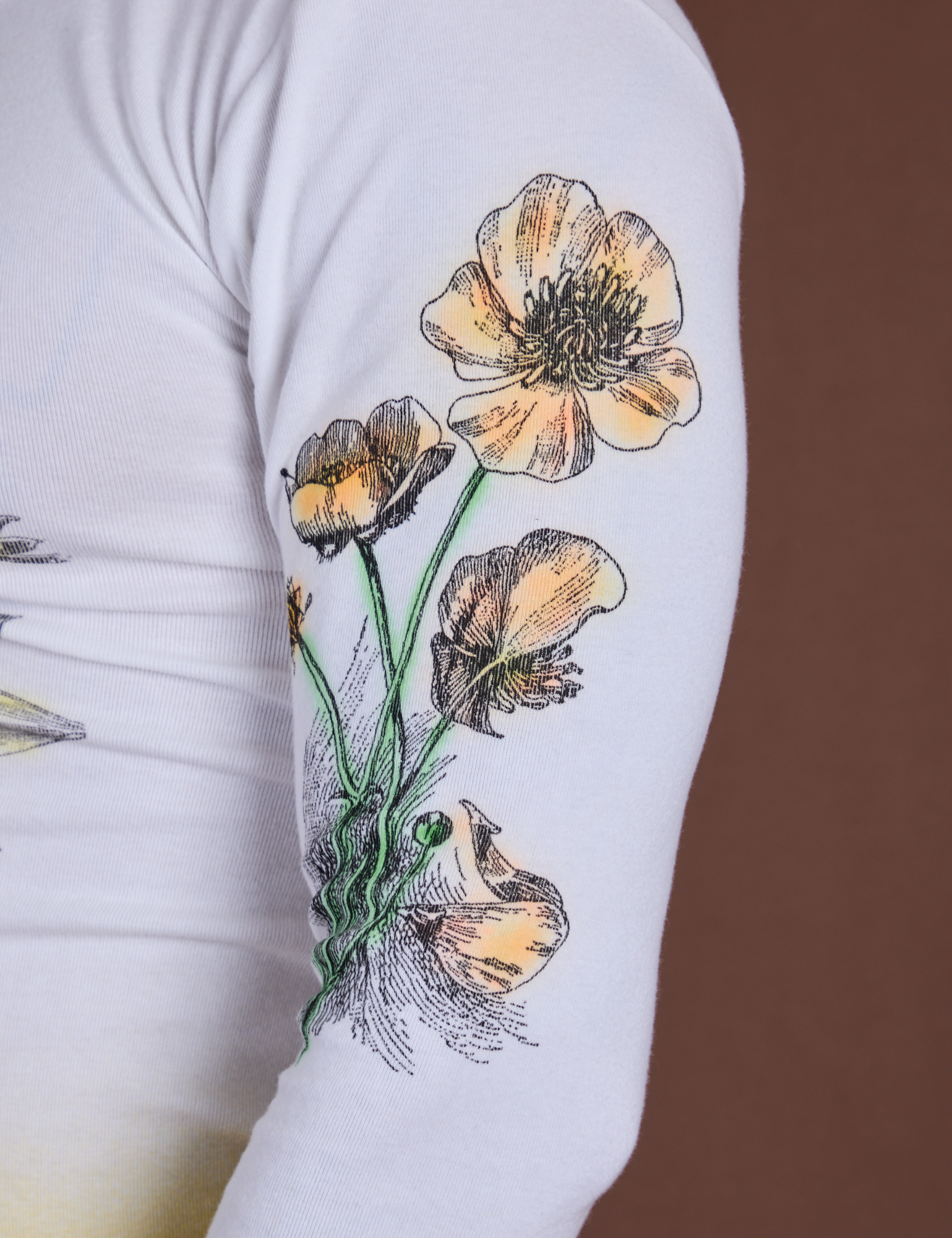 Close up of screen-printed flower on sleeve of Floral Long Sleeve Baby Tee in Yellow