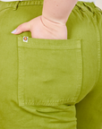 Work Pants in Gross Green back pocket close up. Ashley has her hand in the pocket.