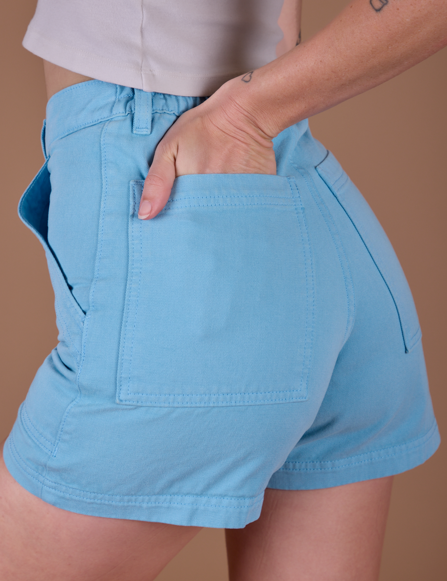 Close up of Alex's hand in the back pocket of Classic Work Shorts in Baby Blue