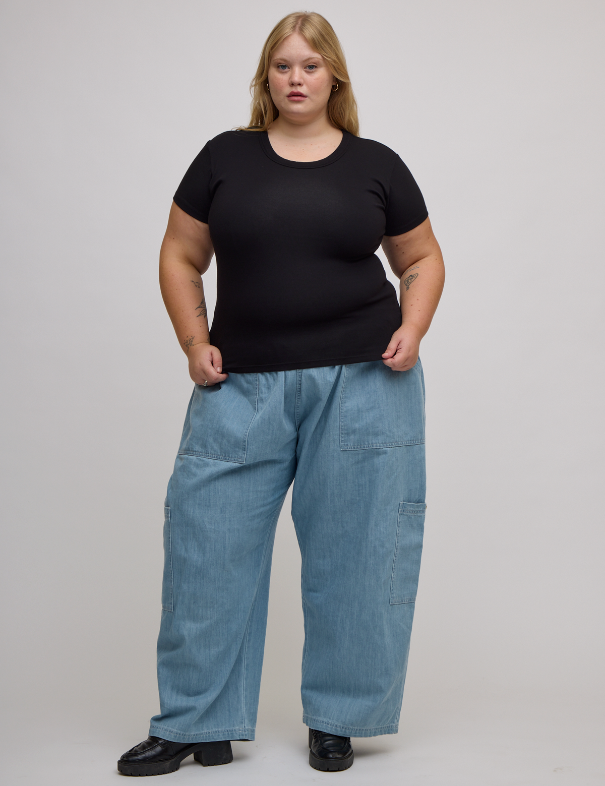Juliet is wearing Baby Tee in Basic Black and light wash denim drop pocket pants