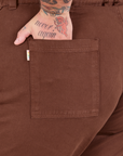 Bell Bottoms in Fudgesicle Brown back pocket close up. Sam has their hand in the pocket.