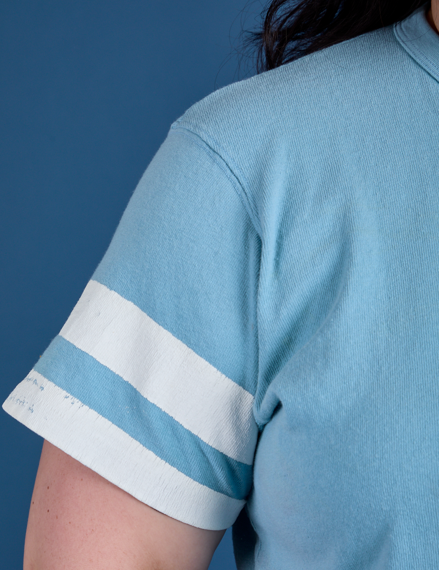 Painted Burly Tee in Baby Blue sleeve close up with two white painted stripes on Ashley