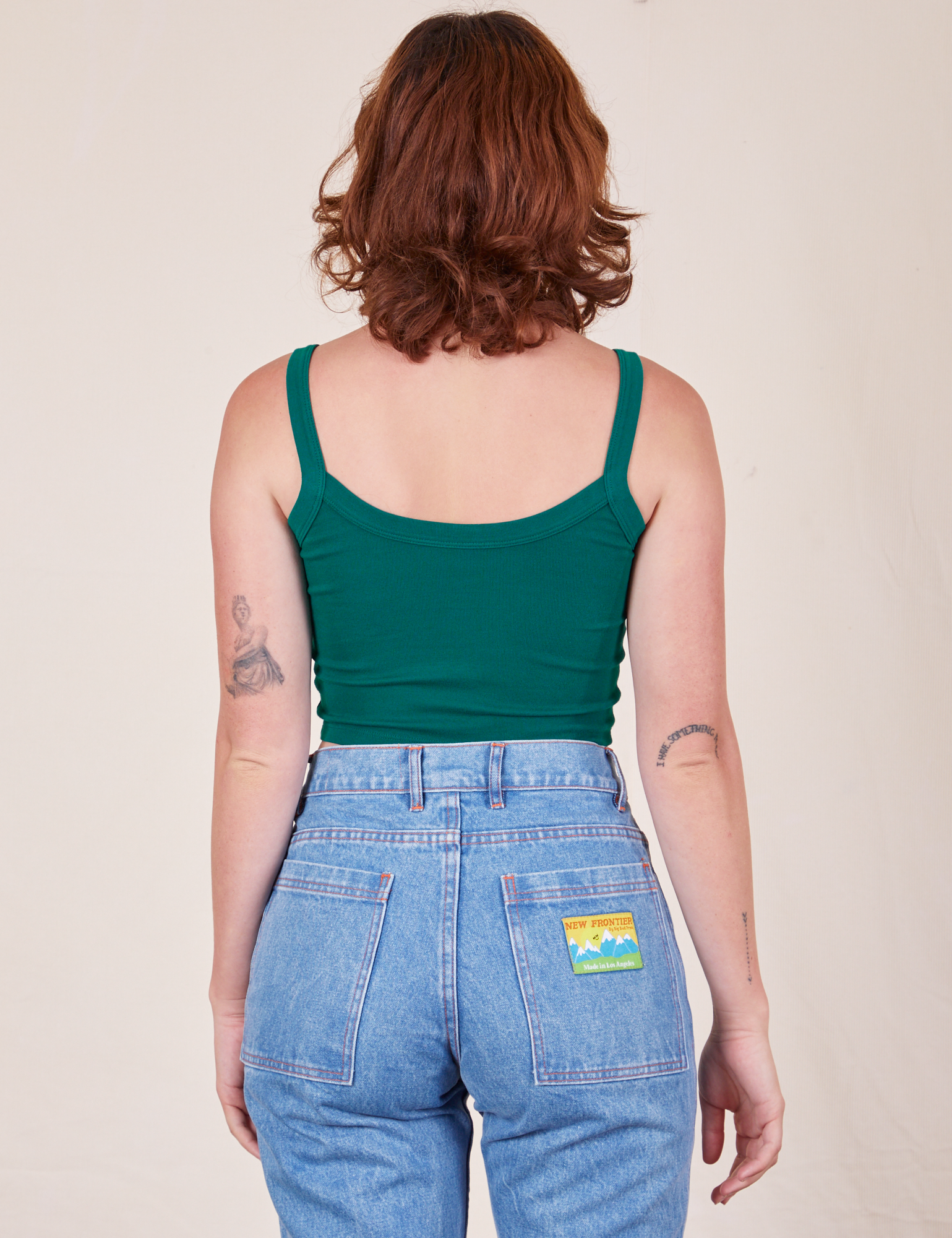 Back view of Cropped Cami in Hunter Green and light wash Frontier Jeans worn by Alex.