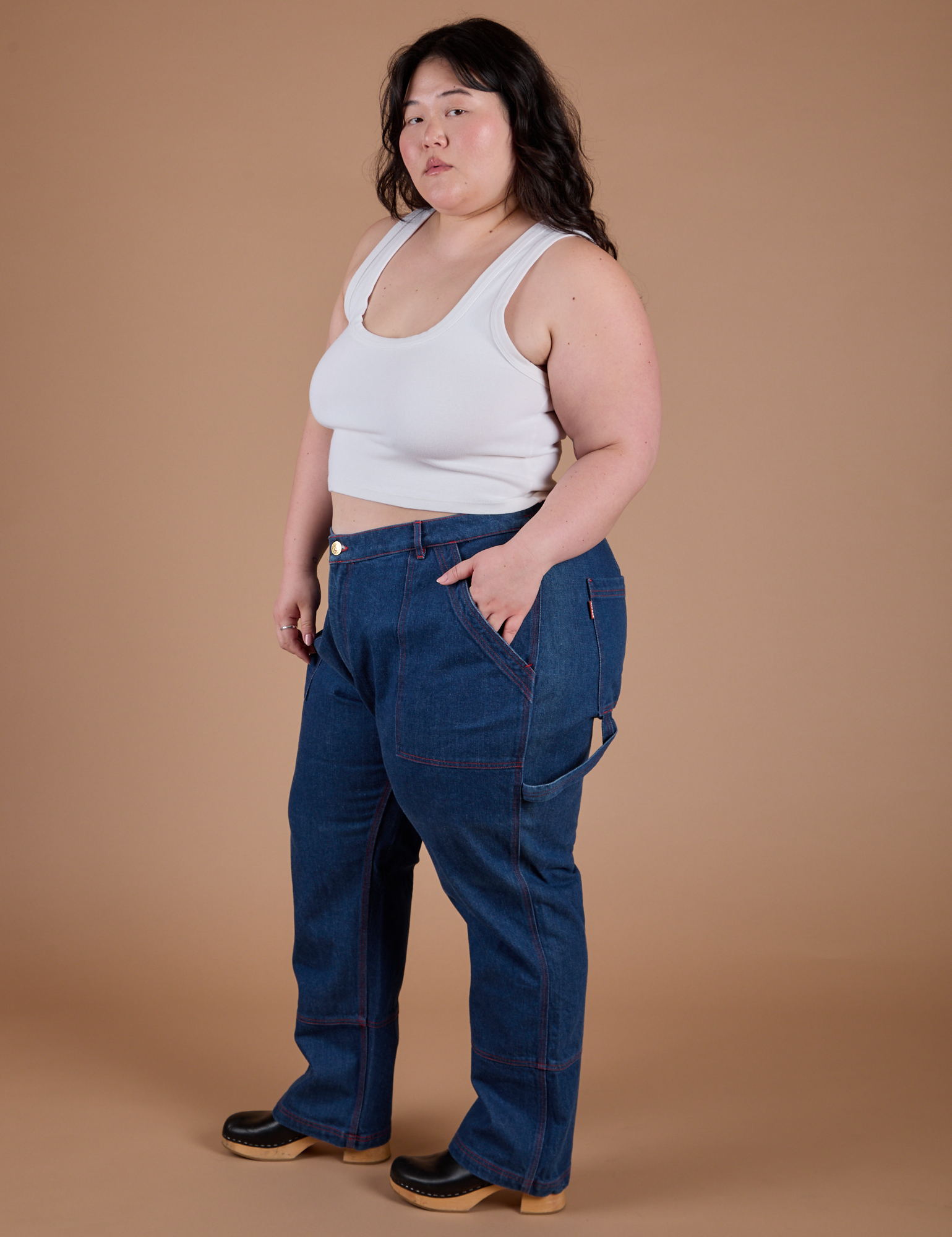 Angled front view of Carpenter Jeans in Dark Wash and Cropped Tank in Vintage Tee White on Ashley