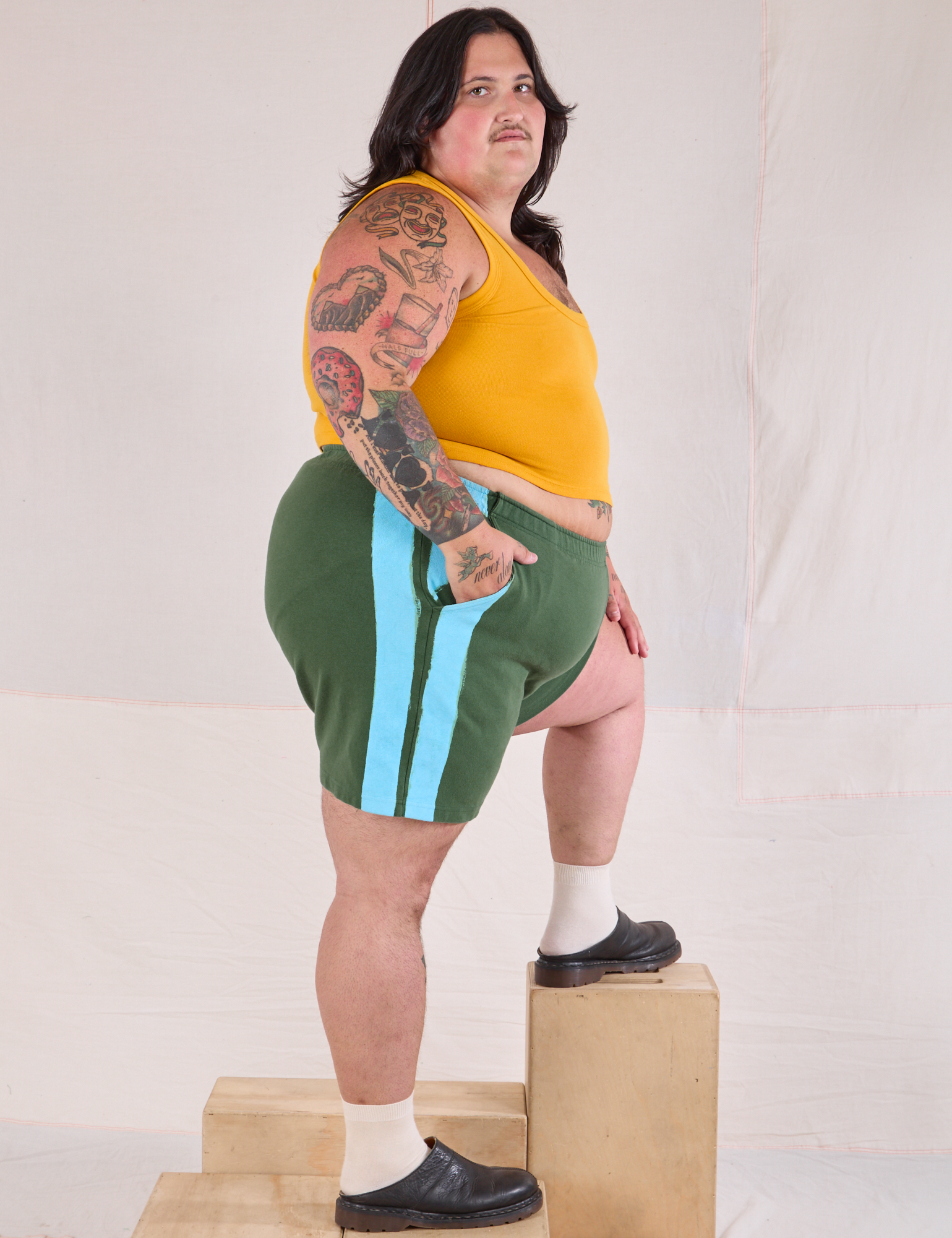 Side view of Painted Stripe Easy Shorts in Dark Emerald Green and golden yellow Cropped Tank on Sam