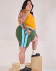 Side view of Painted Stripe Easy Shorts in Dark Emerald Green and golden yellow Cropped Tank on Sam