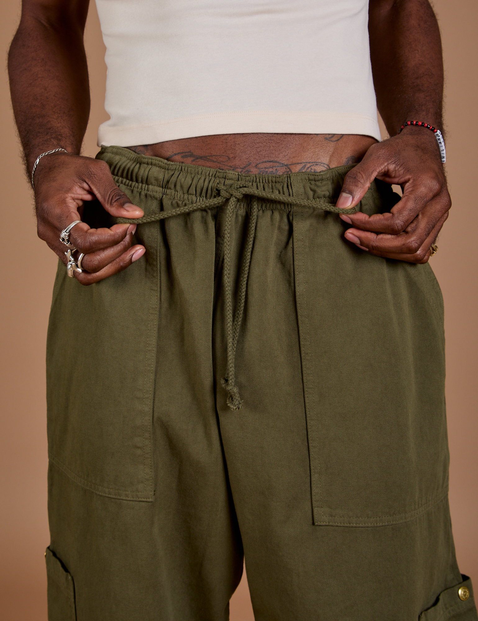 Drop Pocket Cargo Pants in Surplus Green front close up with Jerrod holding the cotton drawstring