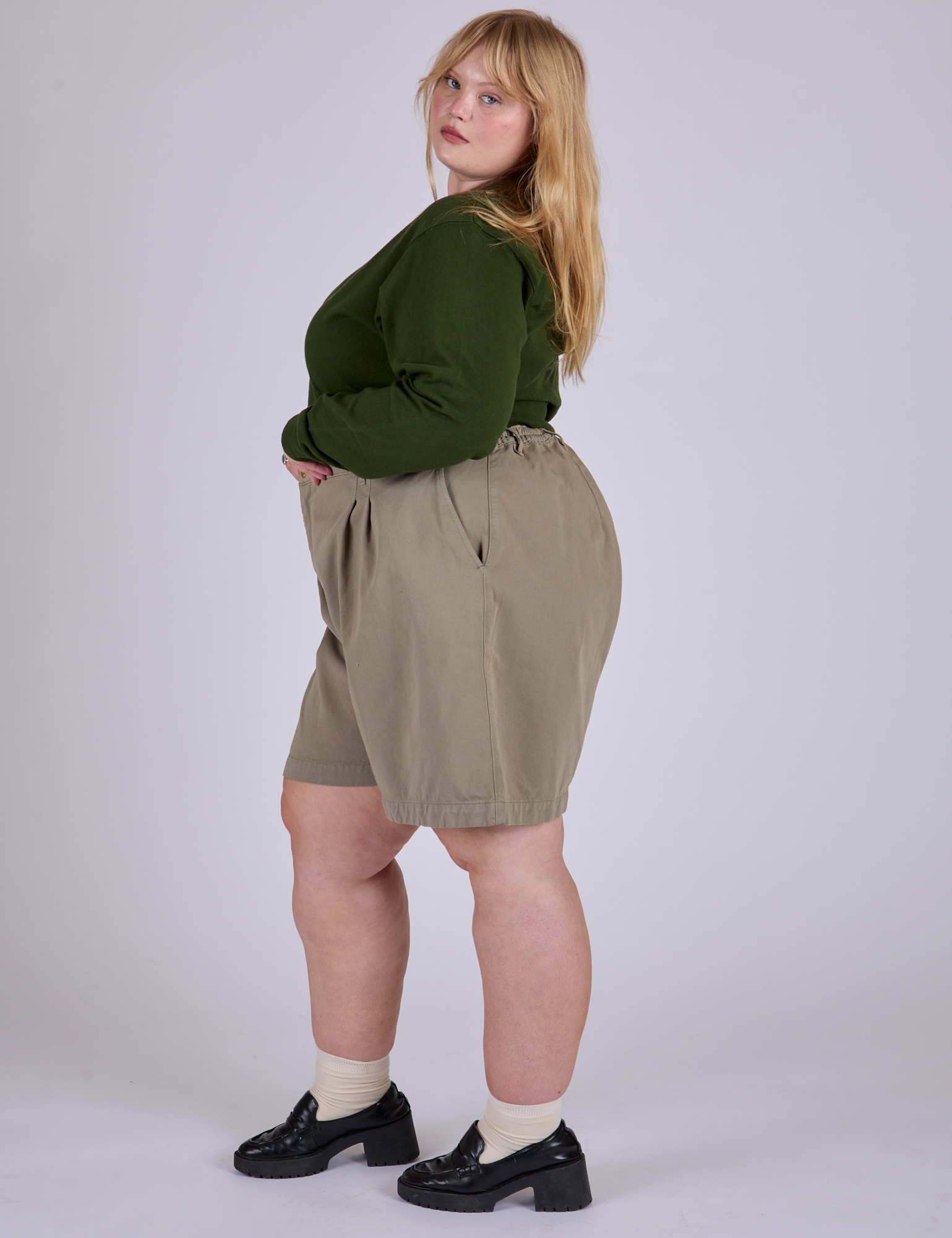 Side view of Pleated Trouser Shorts in Khaki Grey and evergreen Long Sleeve Burly Tee on Juliet