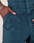 Close up of Jerrod's hand in the front pocket of a Long Jumpsuit in Lagoon