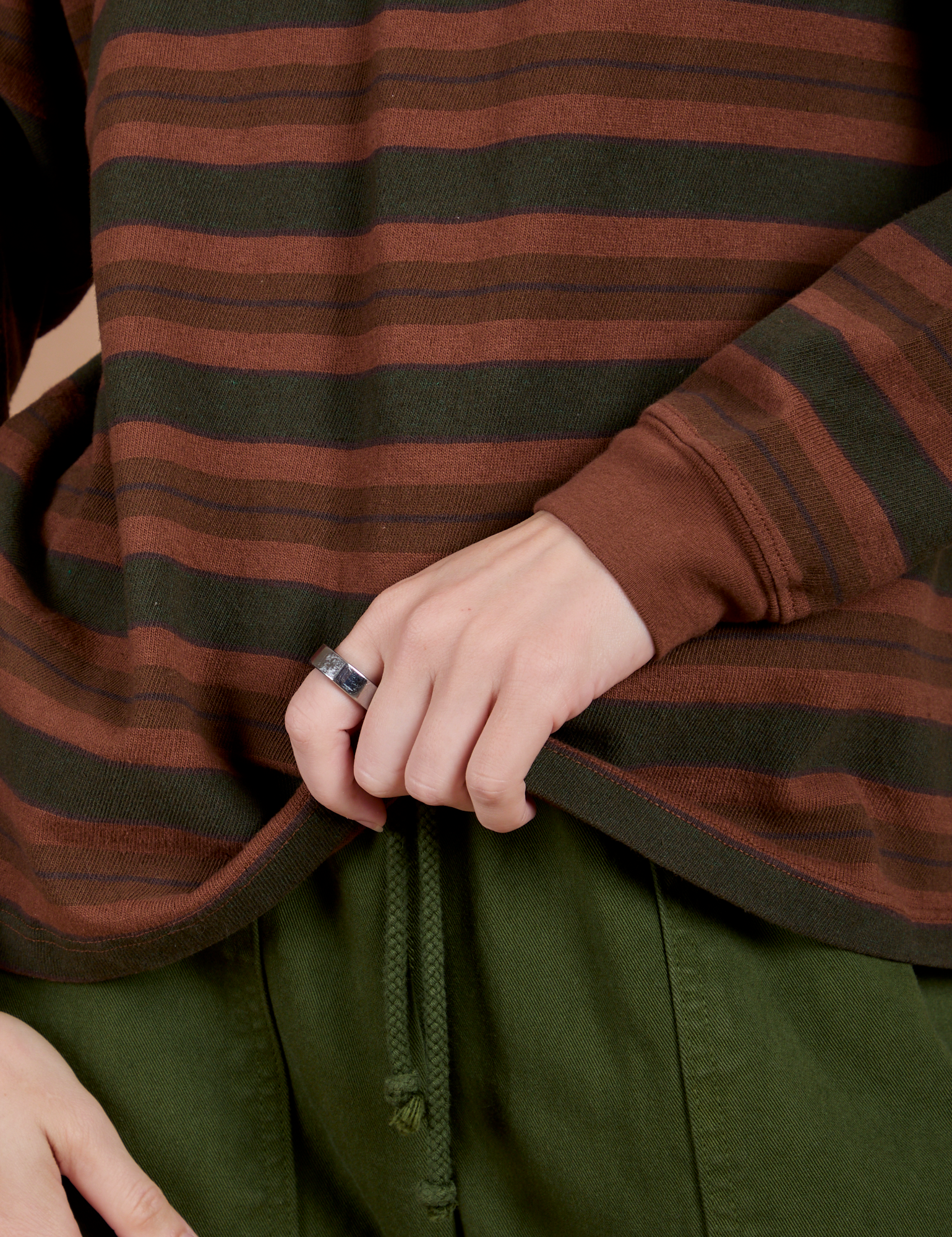 Long Sleeve Striped Burly Tee in Fudgesicle bottom close up with Alex holding the hem
