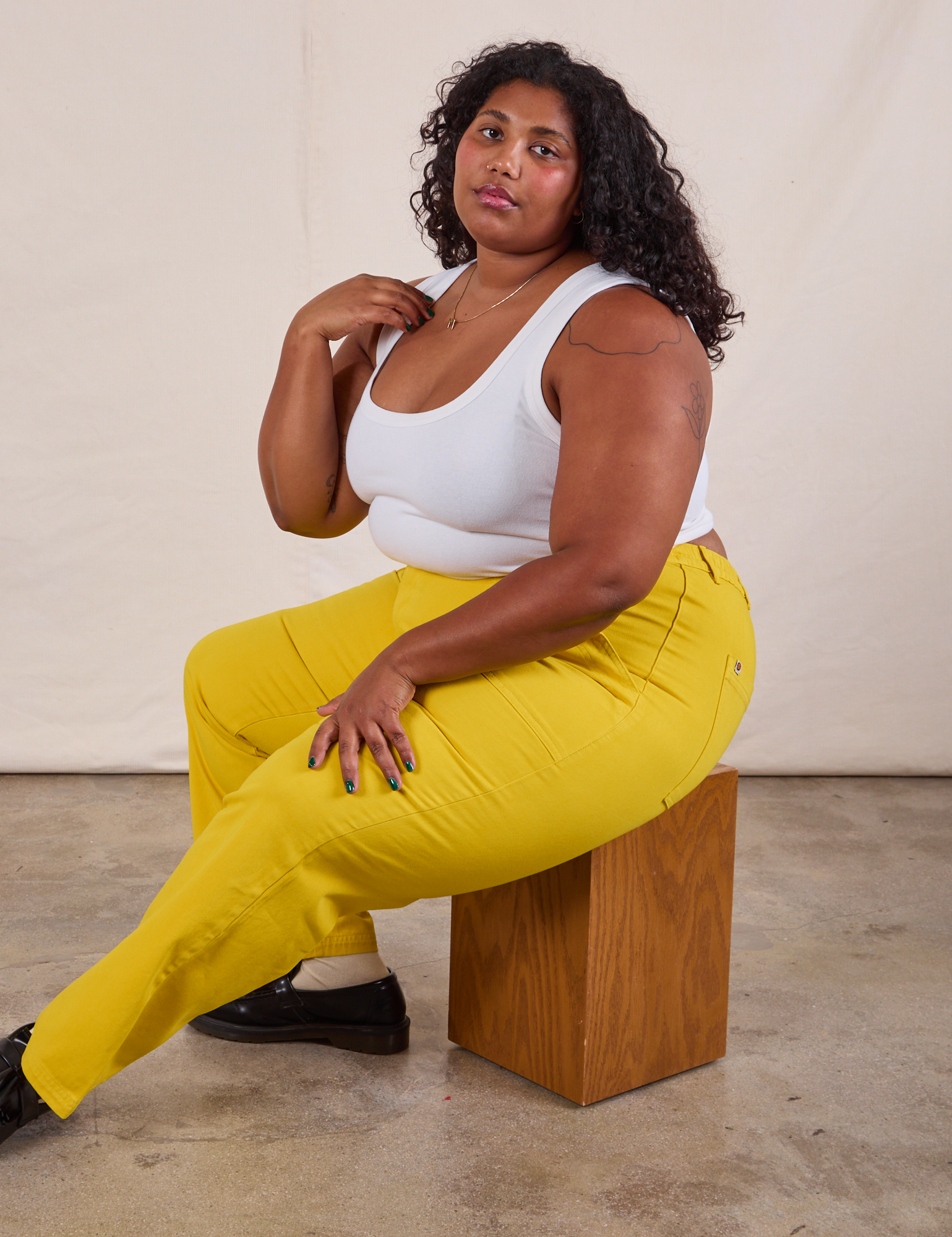 Work Pants in Golden Yellow on Morgan sitting on a wooden box