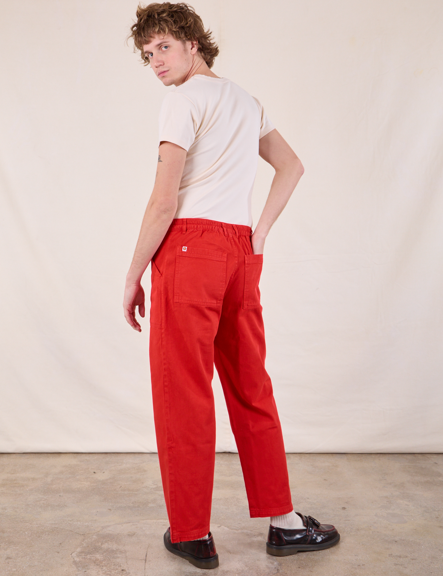 Angled back view of Work Pants in Mustang Red and Burly Tee in Vintage Tee Off-White