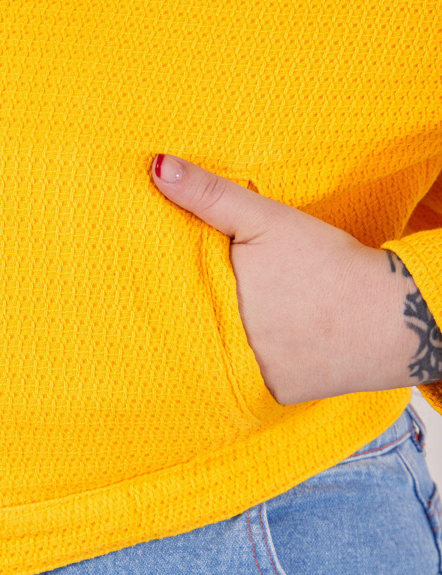 Front pocket close up of the Ricky Jacket in Sunshine Yellow. Sydney has her hand in the pocket