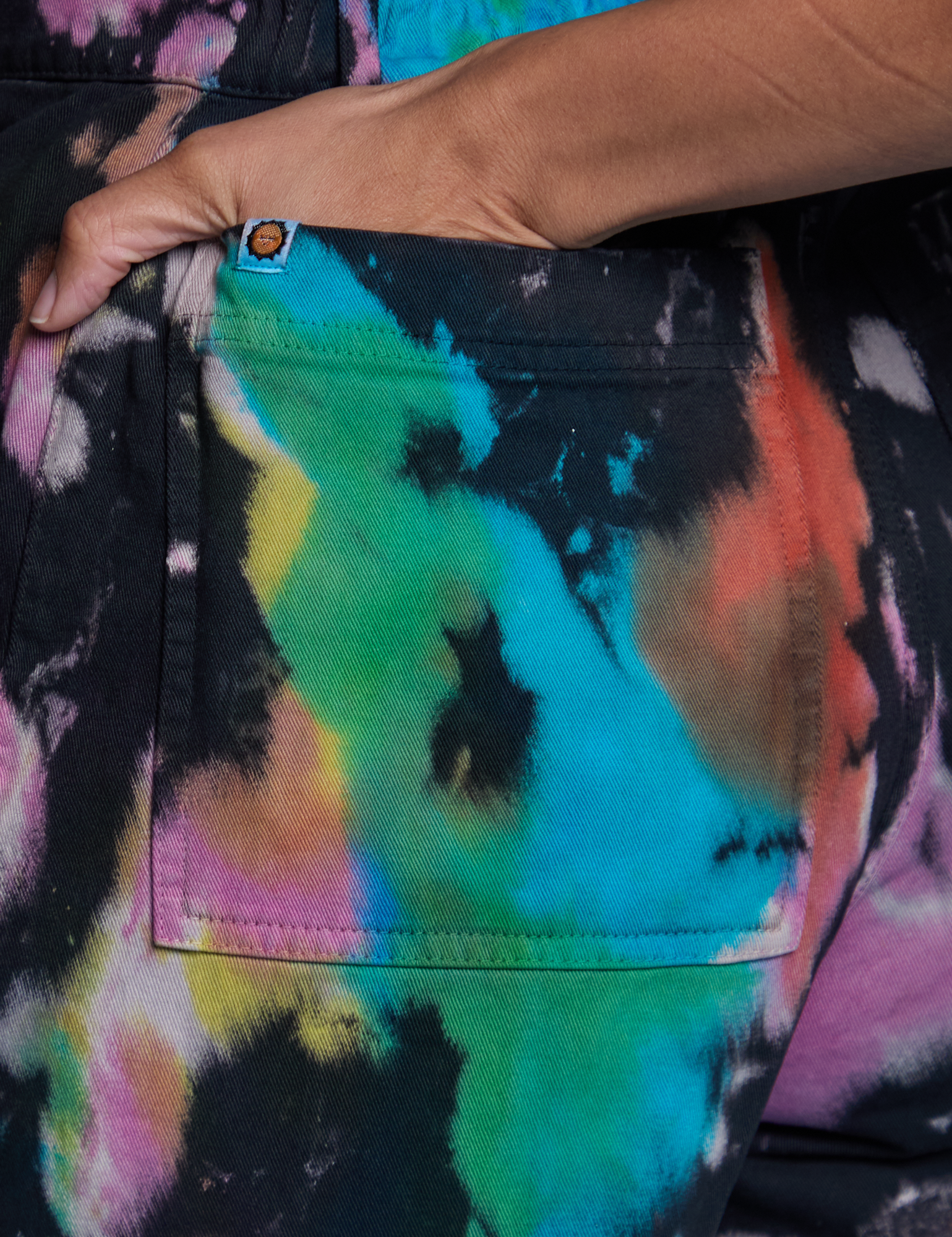 Close up of Tiara&#39;s hand in the back pocket of Short Sleeve Jumpsuit in Rainbow Magic Waters