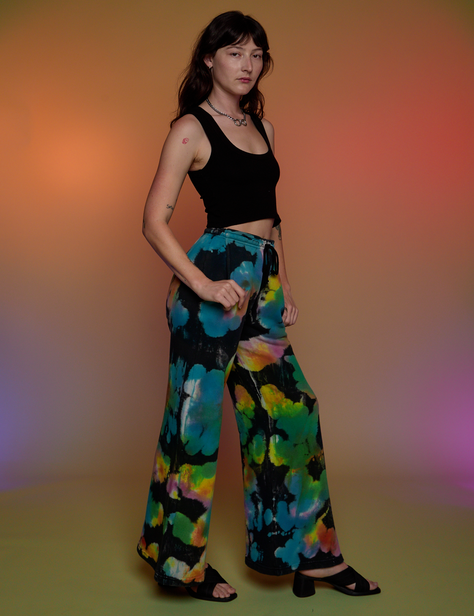 Side view of Tie Dyed Wide Leg Sweat Pants and black Cropped Tank on Alex
