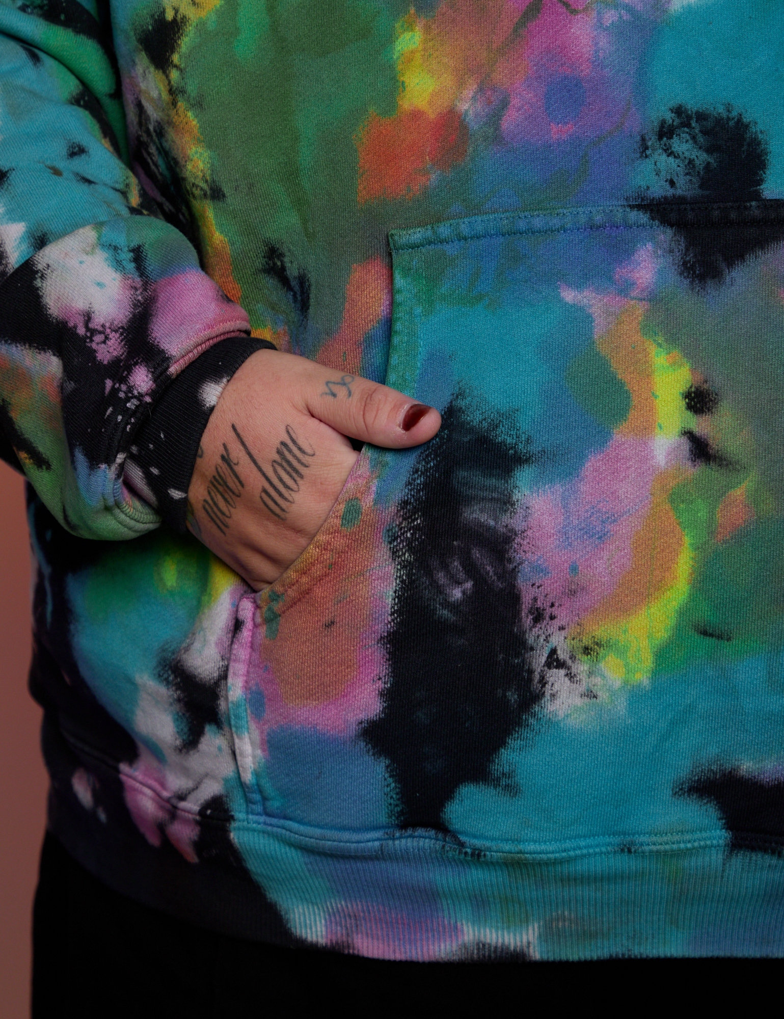 Close up of Sam&#39;s hand in the front pocket of Oversized Hoodie in Rainbow Magic Waters