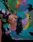 Close up of Sam's hand in the front pocket of Oversized Hoodie in Rainbow Magic Waters