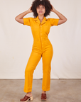 Gabi is 5'7" and wearing XS Short Sleeve Jumpsuit in Mustard Yellow
