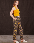 Side view of Marble Splatter Work Pants in Espresso Brown and mustard yellow Tank Top on Scarlett