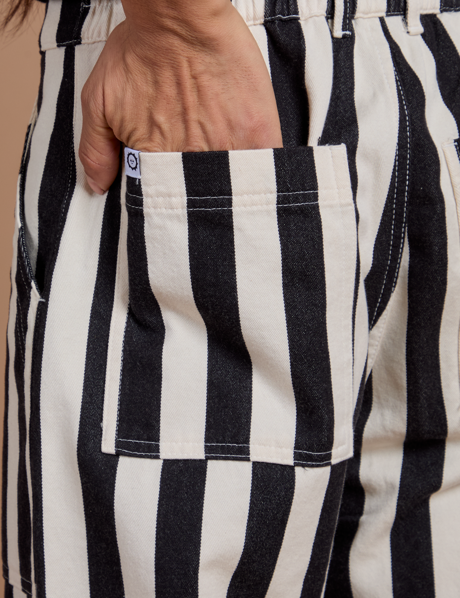 Close up of Anthony's hand in the back pocket of Black Stripe Work Pants in White