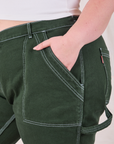 Close up of Ashley's hand in the front pocket of Carpenter Jeans in Swamp Green